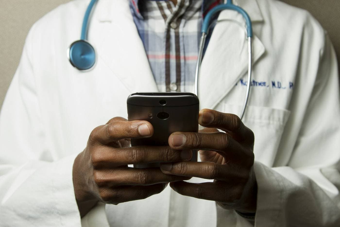 Physician in a white coat holding a phone